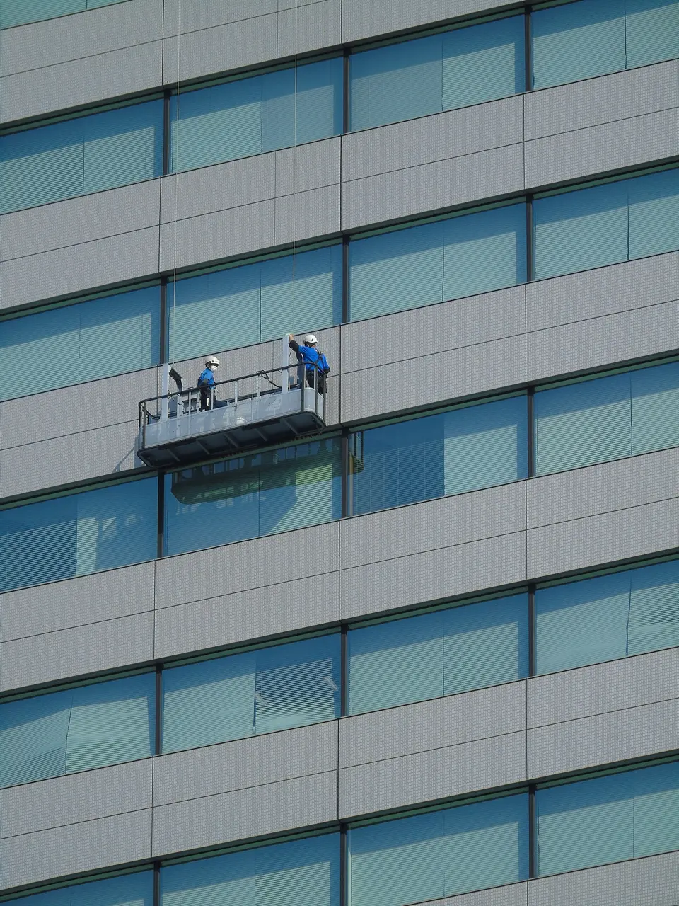 Cleaners on a suspended platform cleaning a glass facade