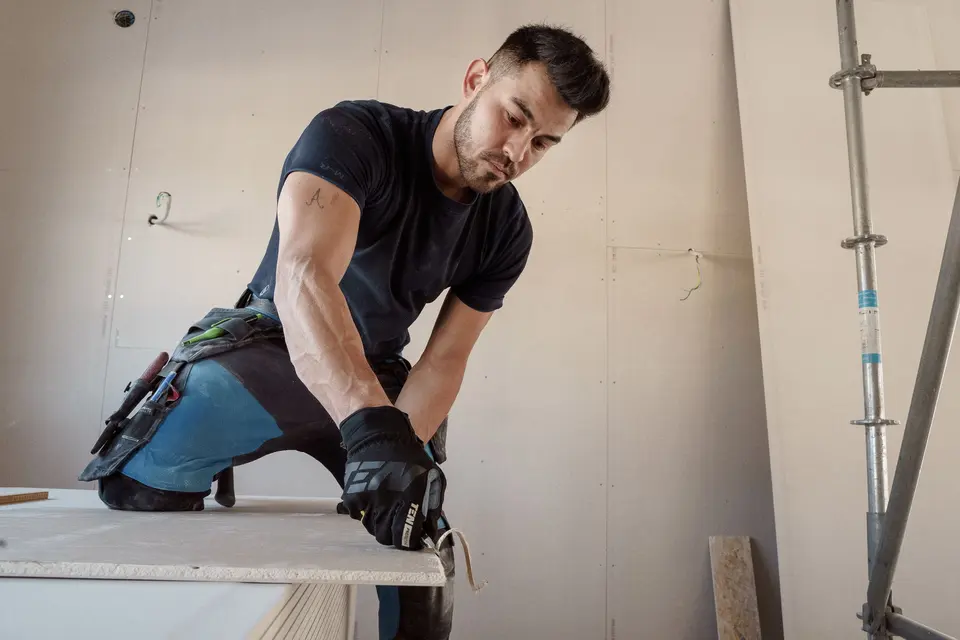 Worker cutting plasterboard for a drywall installation