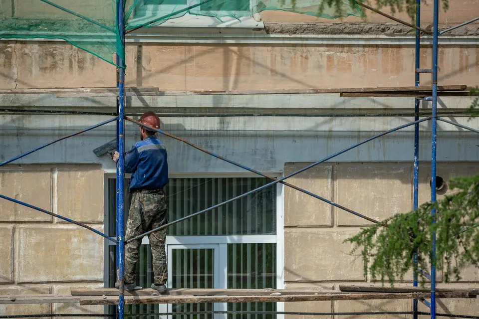 Worker repairing a building facade on scaffolding